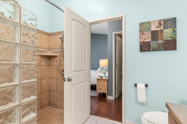 ensuite bathroom with walk in shower, toilet, and baseboards