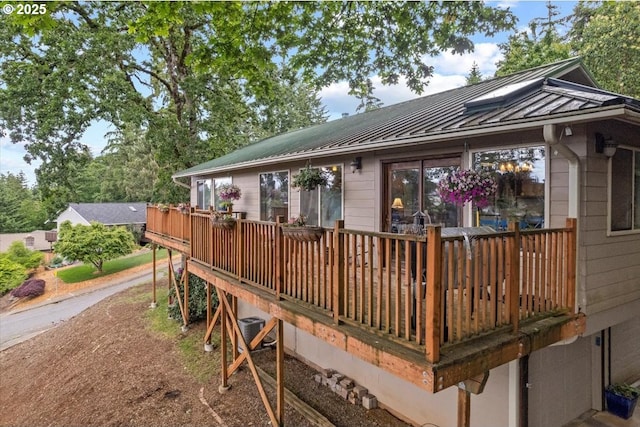 back of house featuring a standing seam roof, a deck, and metal roof