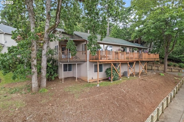 back of house with a deck and view of wooded area