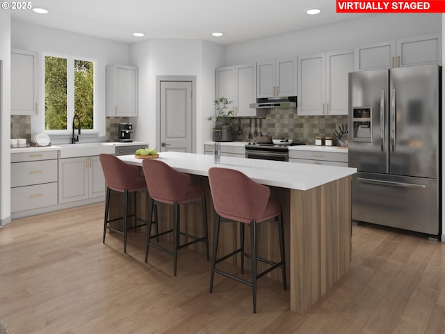 247 NW 29th Way, Battle Ground, WA 98604 - kitchen with stainless steel appliances, under cabinet range hood, a sink, decorative backsplash, and light countertops