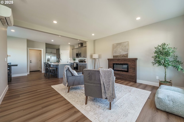 4027 SW Myrtle Aly Unit 7, Gresham, OR 97030 - living area featuring baseboards, a glass covered fireplace, recessed lighting, wood finished floors, and a wall mounted AC