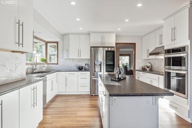 kitchen with white cabinetry, sink, decorative backsplash, a kitchen island, and appliances with stainless steel finishes