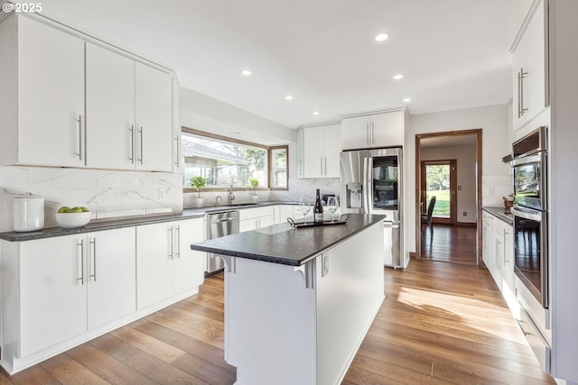 kitchen featuring white cabinets, a center island, stainless steel appliances, and light hardwood / wood-style flooring