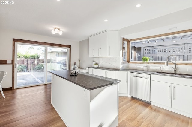 kitchen with stainless steel dishwasher, light hardwood / wood-style floors, white cabinets, and sink