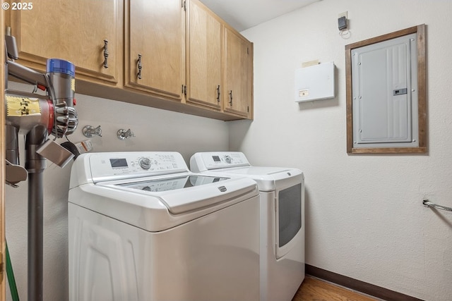 clothes washing area with cabinets, separate washer and dryer, and electric panel