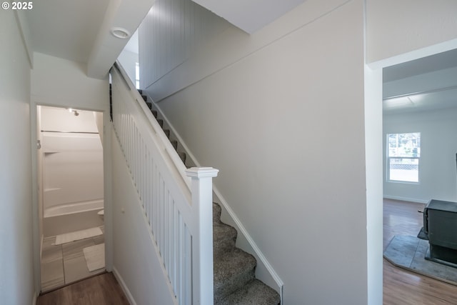 stairs featuring wood finished floors and a wood stove