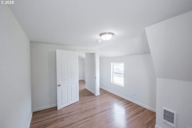 unfurnished bedroom with wood finished floors, baseboards, and vaulted ceiling