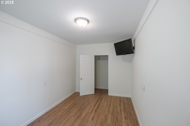 unfurnished bedroom with light wood-type flooring, baseboards, and a closet