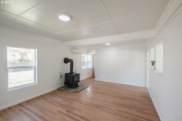 unfurnished living room featuring a wood stove, wood finished floors, and baseboards