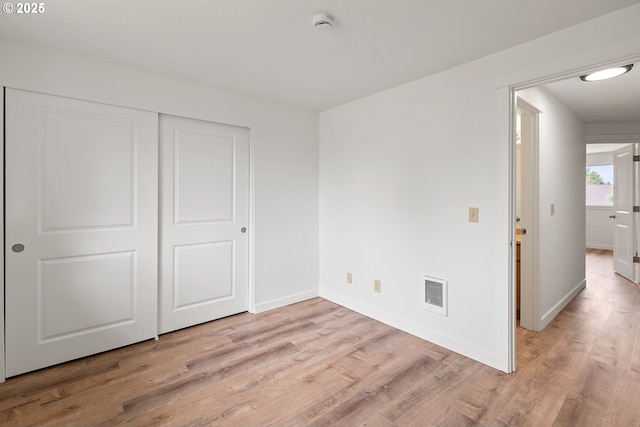 unfurnished bedroom with a closet, baseboards, visible vents, and light wood-type flooring