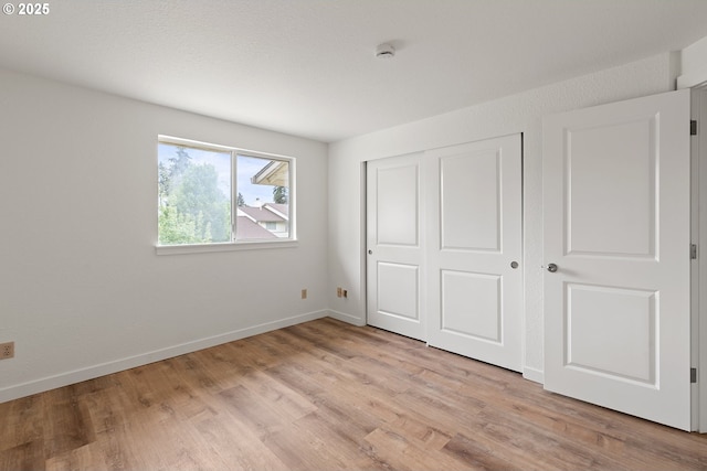 unfurnished bedroom with light wood-style floors, baseboards, and a closet