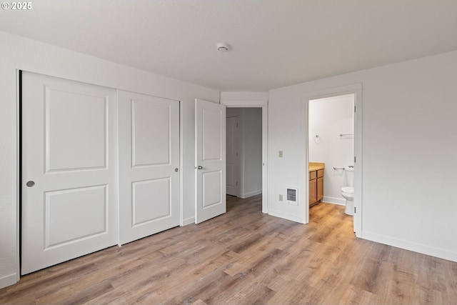 unfurnished bedroom with visible vents, a closet, baseboards, ensuite bathroom, and light wood-type flooring