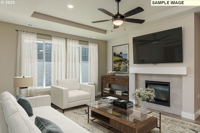 living area featuring a tray ceiling, a ceiling fan, and visible vents