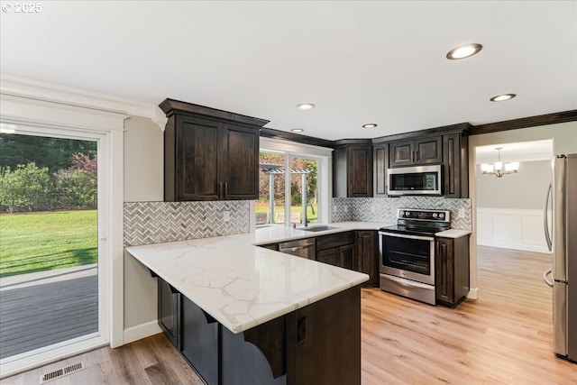 20606 NE 229th St, Battle Ground, WA 98604 - kitchen with crown molding, dark brown cabinets, appliances with stainless steel finishes, a sink, and light wood-style flooring