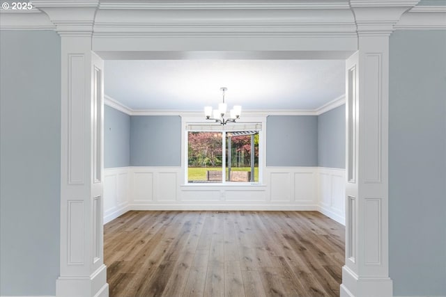 20606 NE 229th St, Battle Ground, WA 98604 - unfurnished dining area featuring ornate columns, a decorative wall, wood finished floors, and an inviting chandelier