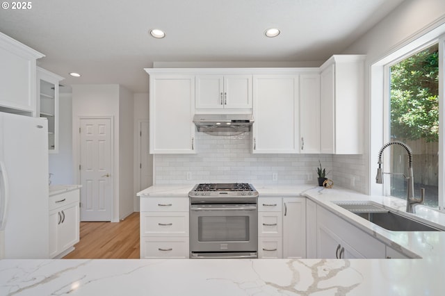 14067 Chatham Ct, Lake Oswego, OR 97035 - kitchen featuring stainless steel gas stove, ventilation hood, freestanding refrigerator, light wood-style floors, and tasteful backsplash