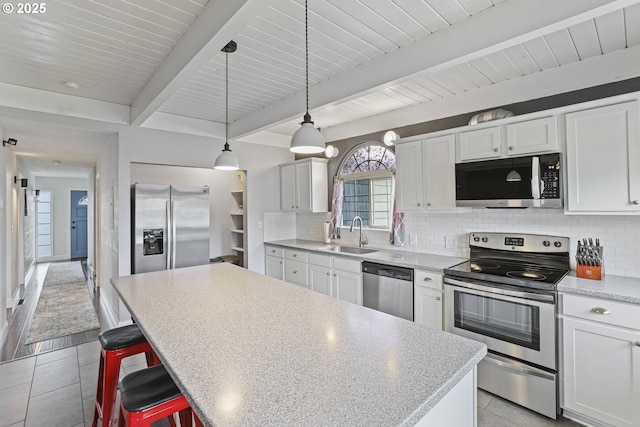2064 Tualatin St, Saint Helens, OR 97051 - kitchen featuring appliances with stainless steel finishes, light tile patterned floors, backsplash, a center island, and a wooden ceiling with exposed beams