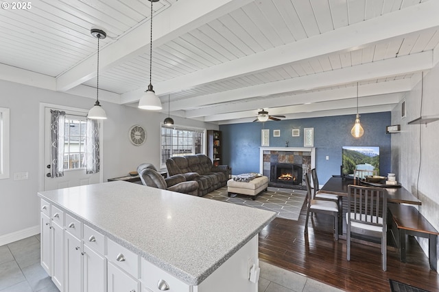 2064 Tualatin St, Saint Helens, OR 97051 - kitchen with a ceiling fan, a center island, a warm lit fireplace, white cabinets, and pendant lighting