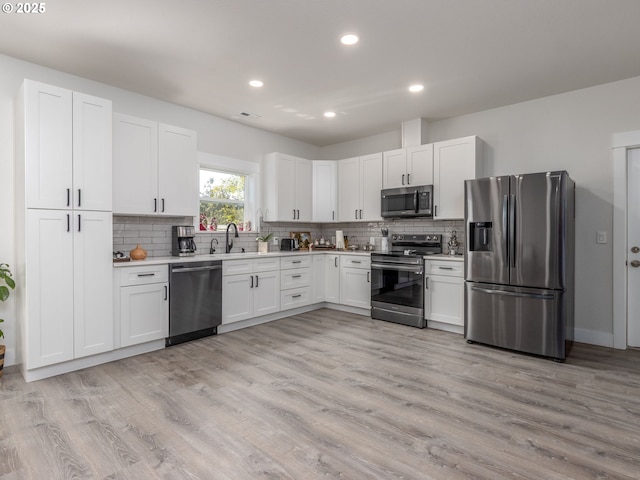 15807 SE Rainier Ave, Clackamas, OR 97015 - kitchen with appliances with stainless steel finishes, light countertops, recessed lighting, backsplash, and light wood finished floors