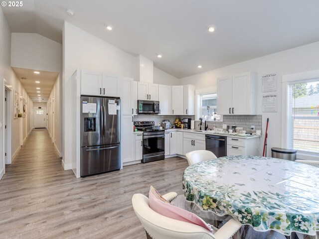 15807 SE Rainier Ave, Clackamas, OR 97015 - kitchen featuring appliances with stainless steel finishes, vaulted ceiling, plenty of natural light, tasteful backsplash, and white cabinets