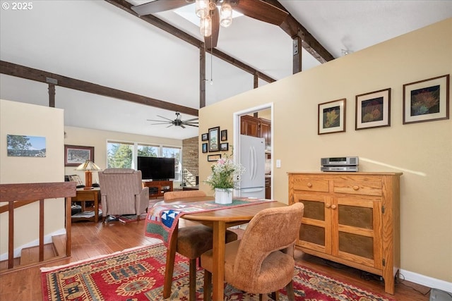 dining room featuring ceiling fan, high vaulted ceiling, wood finished floors, baseboards, and beamed ceiling