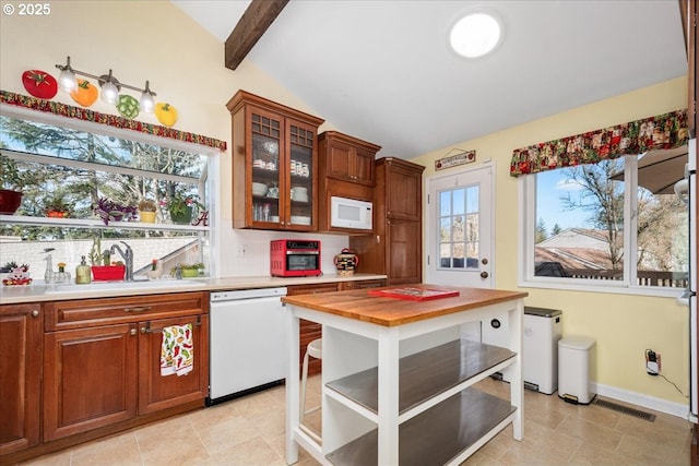 kitchen featuring white appliances, glass insert cabinets, vaulted ceiling with beams, light countertops, and a sink