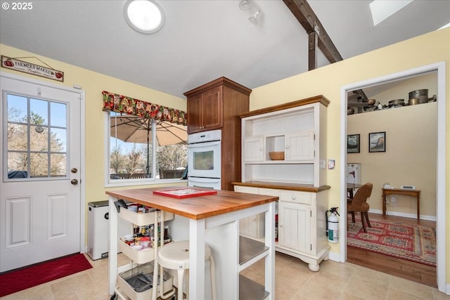 kitchen with light tile patterned floors, double oven, and wood counters