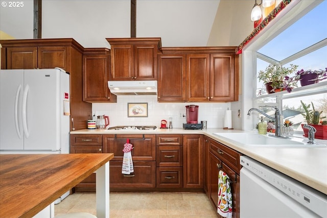 kitchen with white appliances, light countertops, a sink, and under cabinet range hood