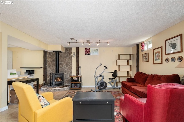 living area with a wood stove, track lighting, baseboards, and a textured ceiling