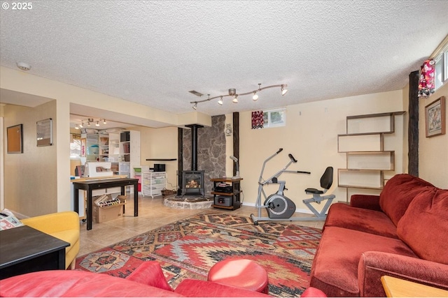 living area with a textured ceiling, a wood stove, and tile patterned floors