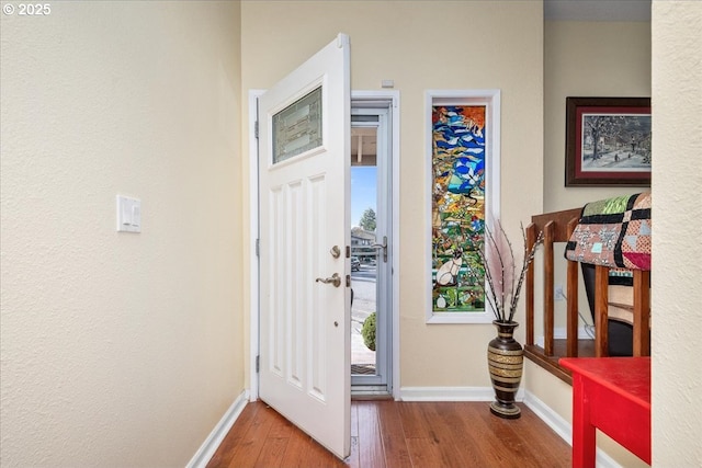 foyer entrance featuring wood-type flooring and baseboards