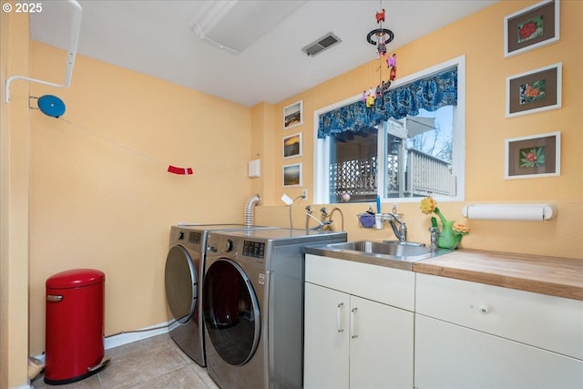 clothes washing area with cabinet space, visible vents, separate washer and dryer, a sink, and light tile patterned flooring