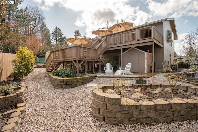 back of property featuring a storage shed, a fire pit, stairs, fence, and a deck