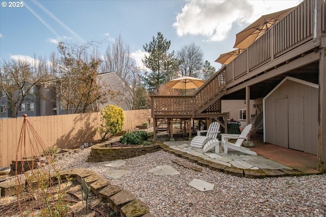 view of yard featuring a wooden deck, fence, stairway, and a patio