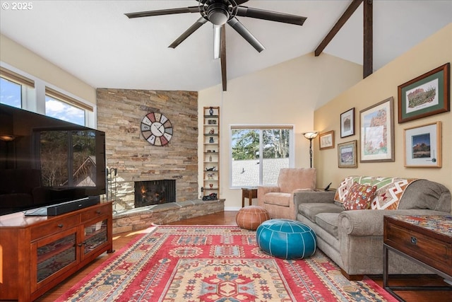 living room featuring a ceiling fan, lofted ceiling with beams, wood finished floors, a stone fireplace, and built in shelves