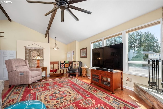 living area featuring a healthy amount of sunlight, wood finished floors, and beamed ceiling