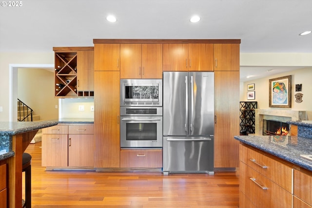 17810 Sarah Hill Ln, Lake Oswego, OR 97035 - kitchen with appliances with stainless steel finishes, light wood-type flooring, recessed lighting, dark stone counters, and brown cabinetry