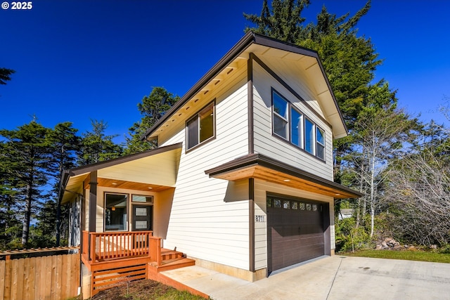 view of front of house with a porch, concrete driveway, fence, and a garage