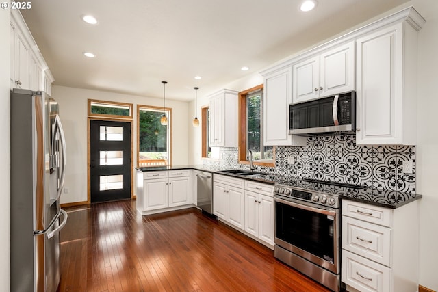 kitchen featuring dark countertops, a peninsula, appliances with stainless steel finishes, and a sink