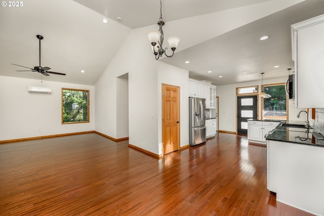 kitchen featuring a wall unit AC, a healthy amount of sunlight, stainless steel fridge, and a sink