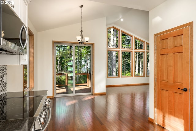 unfurnished dining area with dark wood-style floors, vaulted ceiling, a notable chandelier, and baseboards