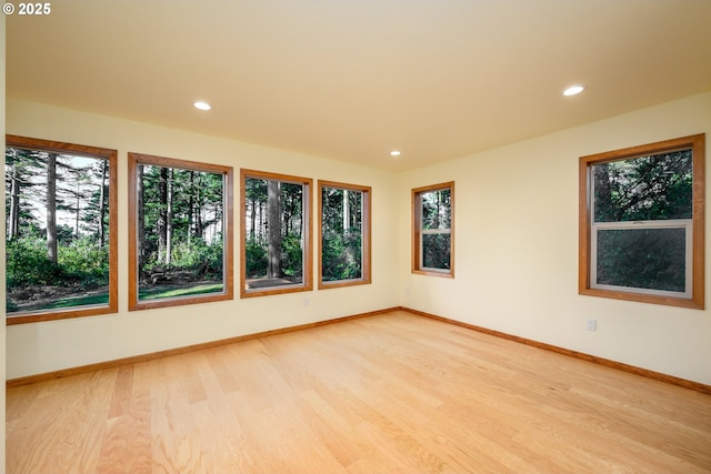 spare room featuring light wood finished floors, baseboards, and recessed lighting