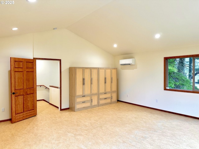 empty room with vaulted ceiling, a wall mounted AC, light carpet, and baseboards