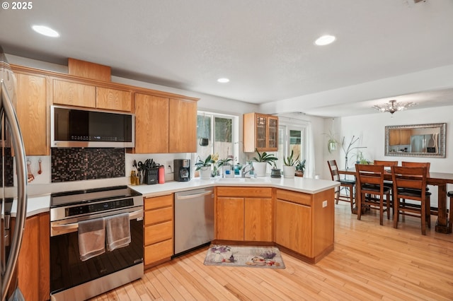 kitchen with light countertops, stainless steel appliances, a sink, and a peninsula