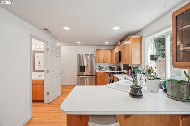 kitchen with visible vents, baseboards, light wood-type flooring, light countertops, and appliances with stainless steel finishes