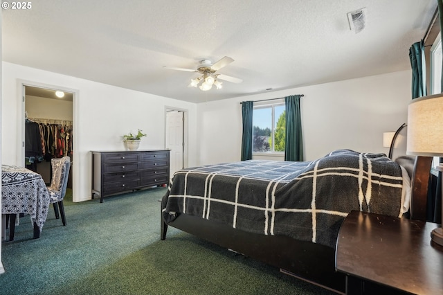 carpeted bedroom with a ceiling fan, visible vents, a walk in closet, and a closet
