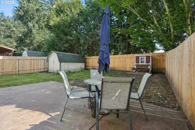view of patio featuring a storage shed, an outdoor structure, outdoor dining area, and a fenced backyard