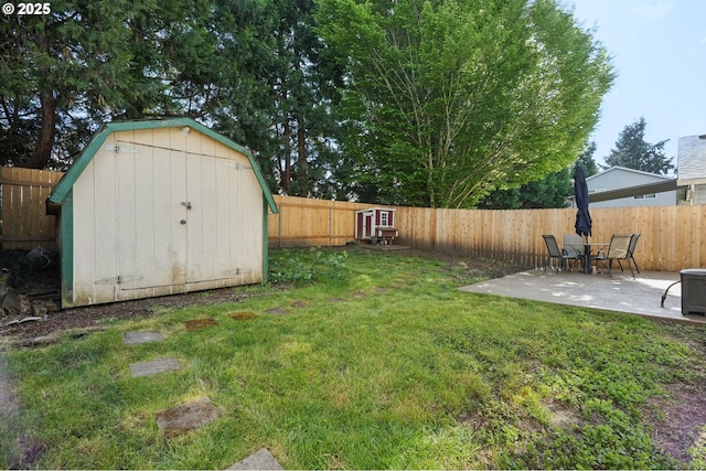 view of yard featuring an outbuilding, a fenced backyard, a patio area, and a storage unit