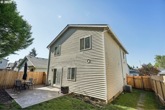 back of house featuring a lawn, central AC unit, a fenced backyard, and a patio area