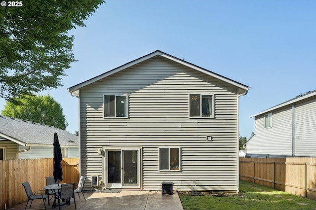 rear view of property with a fenced backyard and a patio